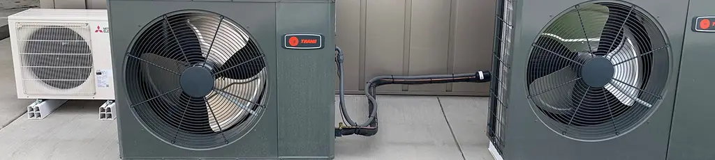 Two Trane condensers and a ductless head along an exterior wall