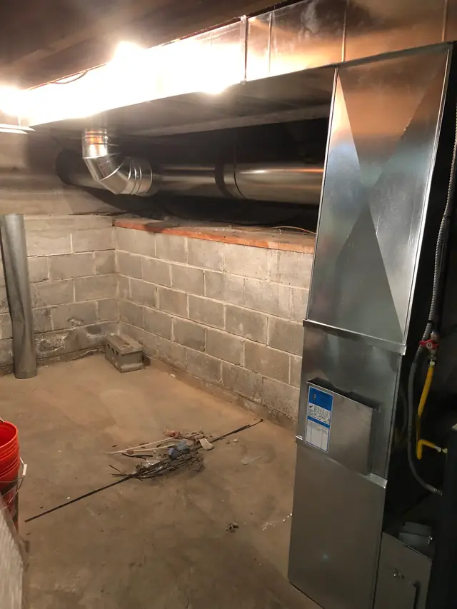 New galvanised trunk line and furnace plenum installed along a basement block wall