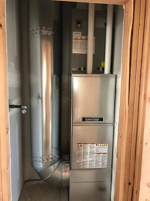 New Ameristar gas furnace with a tall galvanised flue in a framed closet