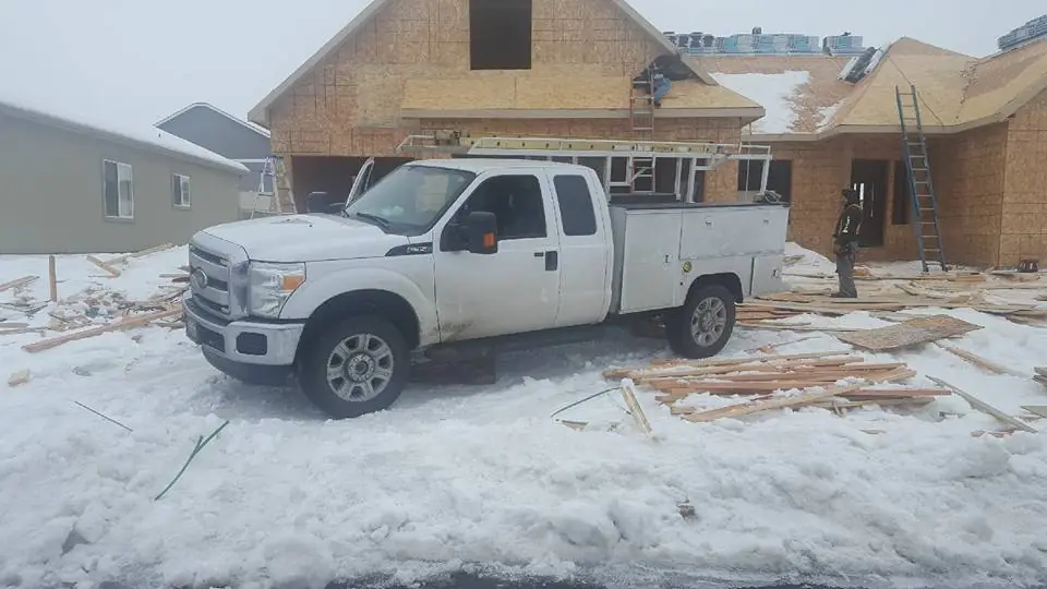 Ice & Fire Mechanical service pickup parked in snow at a framed new-build house